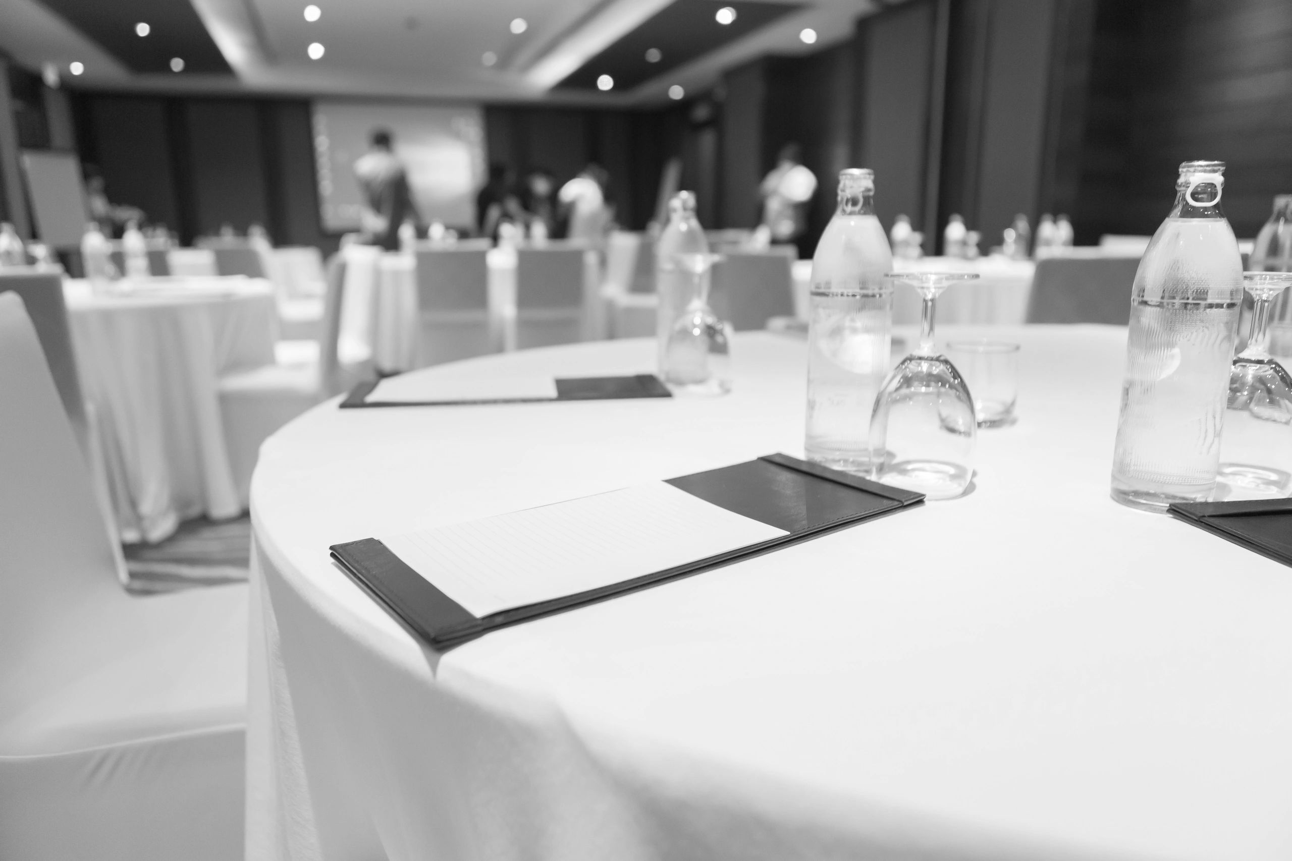 Conference room setup with tables, water bottles, and notepads.