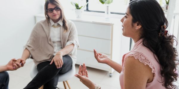Two women engaged in a serious conversation in a bright room.