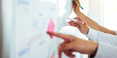 People collaborating and writing on a whiteboard.