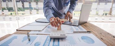 Persona calcula finanzas con gráficos y laptop.