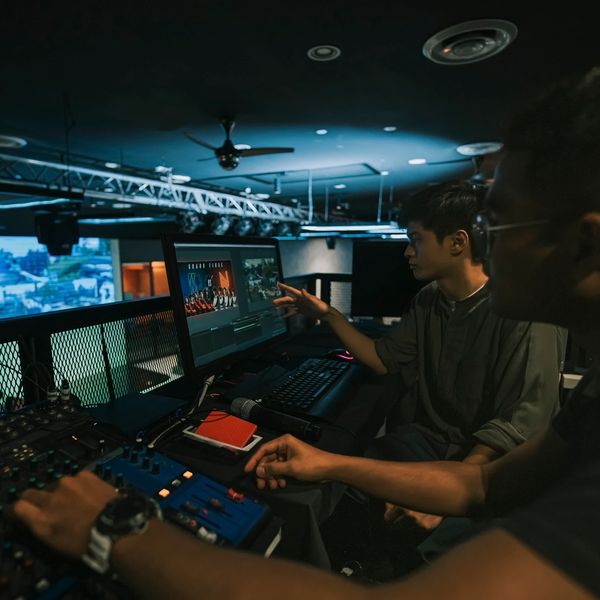 Two men editing video footage in a dimly lit studio.