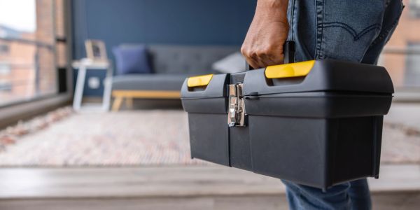 Person carrying a black toolbox indoors.