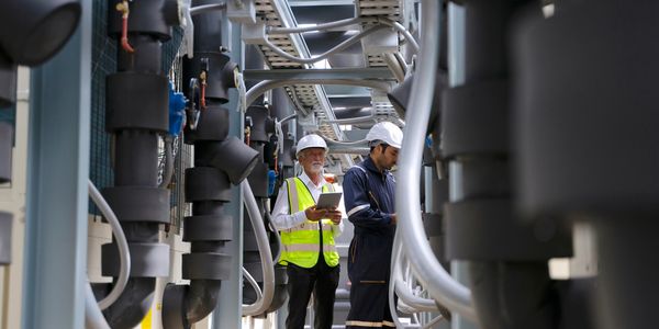 Two engineers inspecting equipment with a tablet.