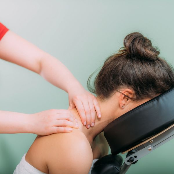 A woman receives a neck and shoulder massage on a massage chair.