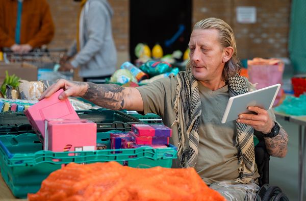 Man in wheelchair shopping for groceries using a tablet.