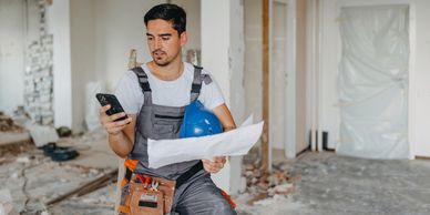 Construction worker checking plans and phone