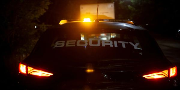 Rear view of a security vehicle with flashing lights at night.