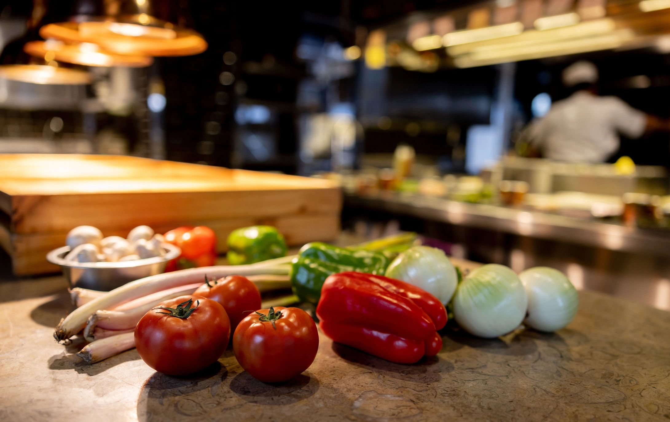Fresh vegetables on a kitchen counter in a busy restaurant kitchen.