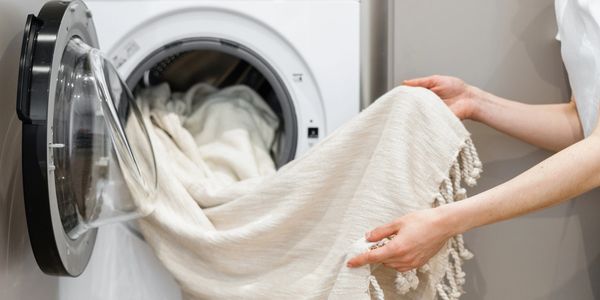 A person is holding onto the towel in front of an open dryer.