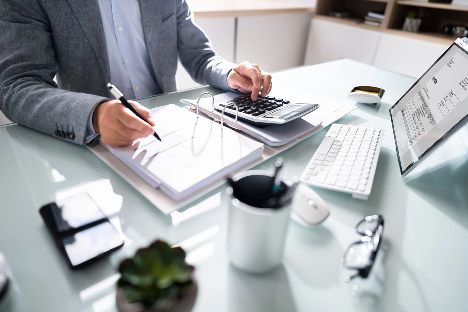 Professional calculating finances with documents and a calculator at a clean desk.