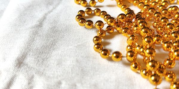Close-up of shiny golden beads on white fabric.
