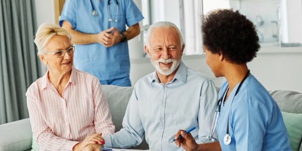 Two senior patients talking with healthcare professionals.