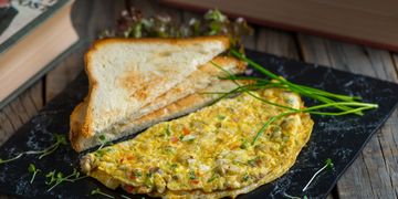 Vegetable omelette served with toasted bread on a black plate.