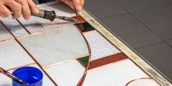 Crafting a stained glass piece with soldering and careful detailing.