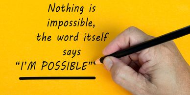 Hand writing the quote "Nothing is impossible, the word itself says I'm possible" on a yellow background.