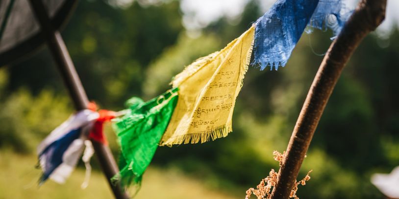Colorful prayer flags fluttering on wooden poles outdoors.