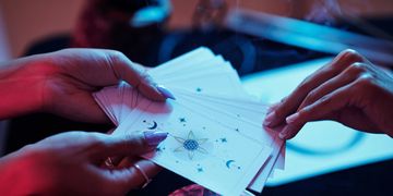 Hands holding and spreading tarot cards during a reading.