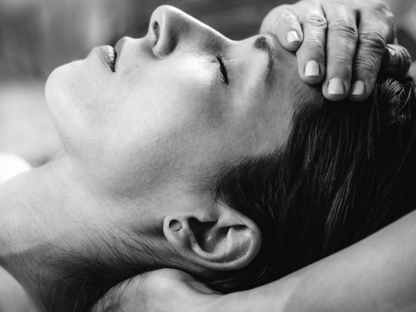 Black and white close-up of a woman receiving a forehead massage.