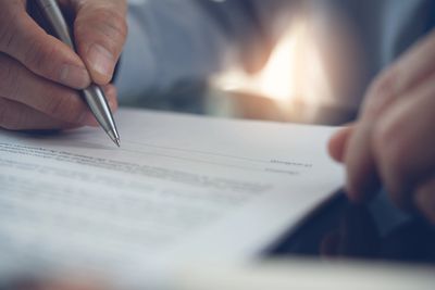 Person signing a document with a pen.