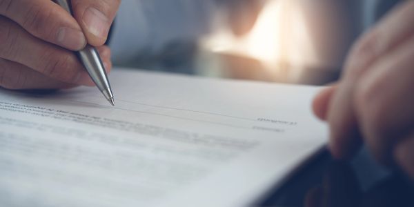 Person signing a document with a pen.