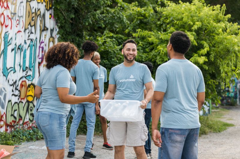 The group of volunteers stand together and discuss how to best divide their tasks for the day.