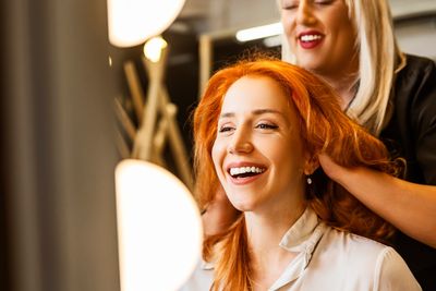 A woman happily getting her hair styled in a salon.