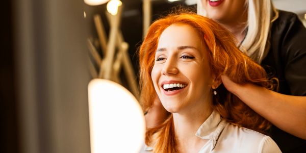 Smiling woman with red hair getting a hair treatment.
