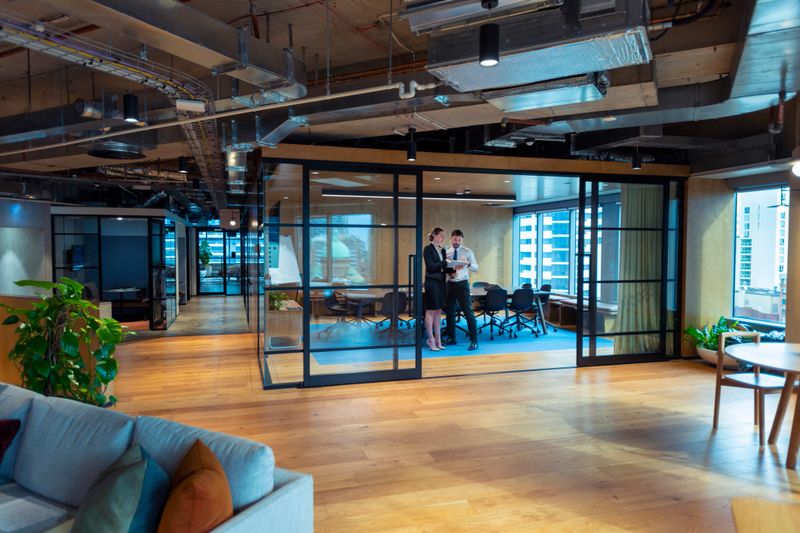 Business Man and woman standing working together on a digital tablet in a board room. They are both well dressed standing in a modern office.