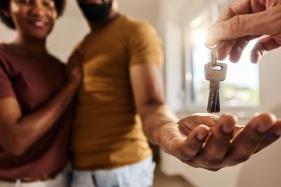 A couple receiving keys to their new home, smiling with excitement.