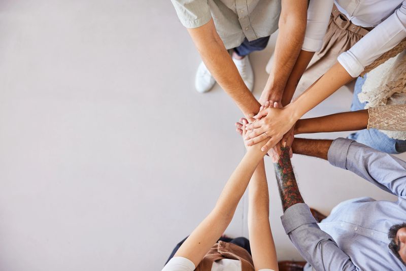 High angle view of a diverse group of unrecognizable businesspeople standing in a huddle with their hands together