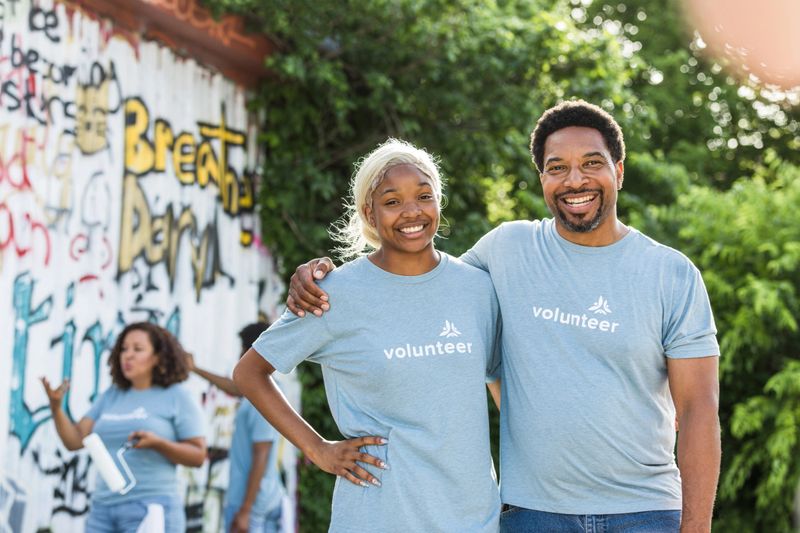 The father and daughter smile proudly as they pose for the camera while they volunteer together.