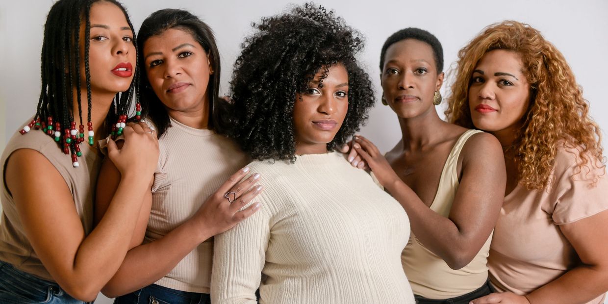 Five diverse women posing together, showing unity and strength.