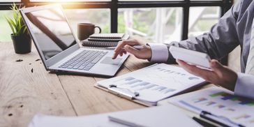 A businessman at a desk with a laptop reviewing documents after a business consulting meeting.