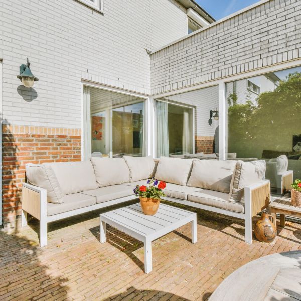 Sunny outdoor patio with white cushioned L-shaped sofa and coffee table.
