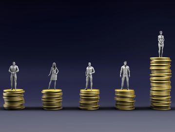 Figurines on stacks of coins showing income disparity between genders.