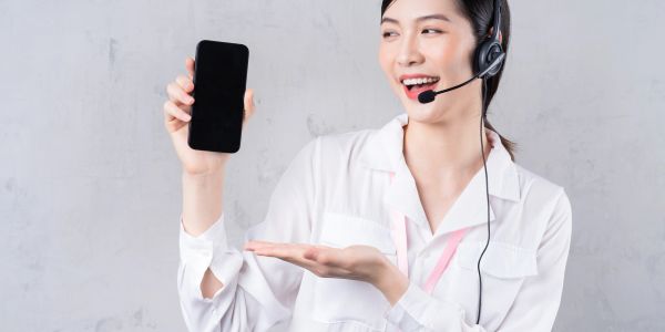 Woman with headset showing a phone.