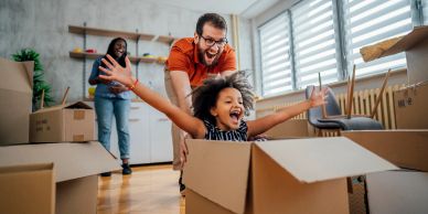 Family playing with moving boxes in a bright home.