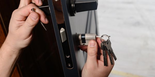 Person fixing a door lock with keys and tools.