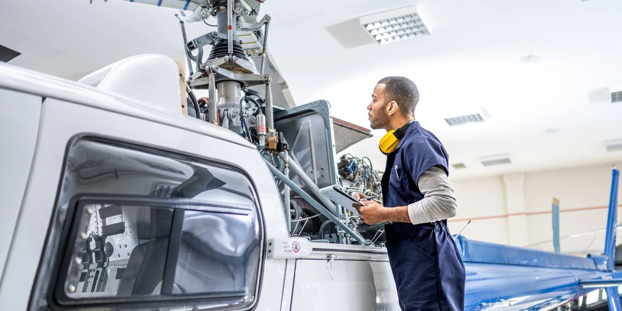 Technician inspects helicopter engine in a hangar.