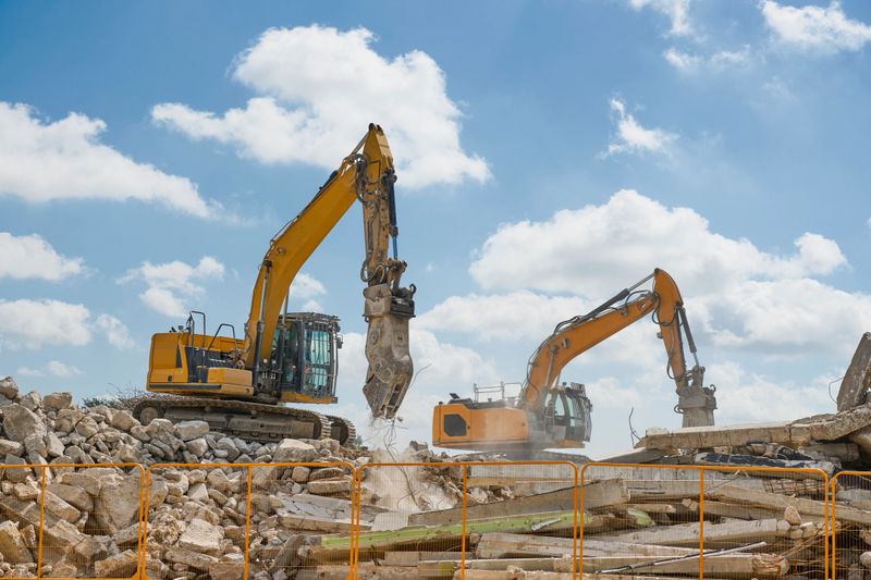 Contractor machines in the process of demolishing old buildings for circular recycling