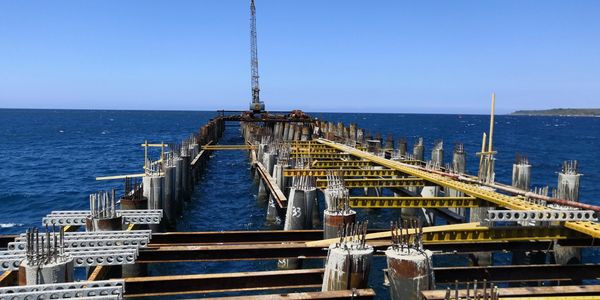 Construction of a pier extending into the ocean under a clear sky.