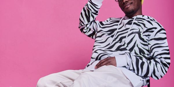 Man in zebra print hoodie against pink background.