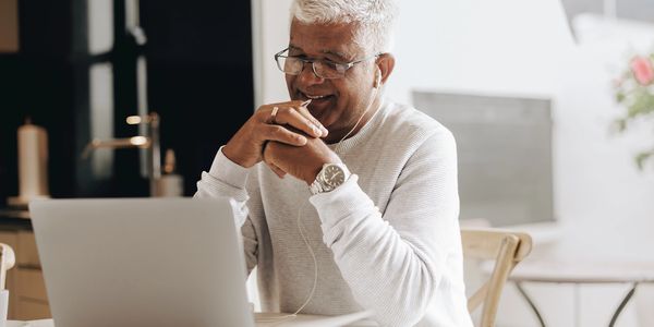 Smiling elderly man enjoying a video call on his laptop.