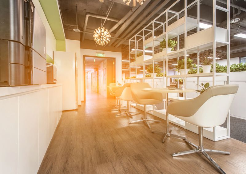 Rest area in modern office interior with swivel chair, round wooden table and coffee