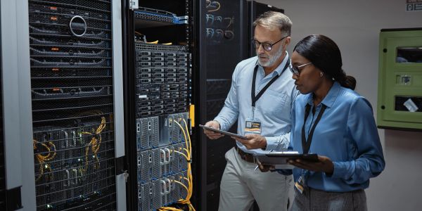 Two IT professionals working in a server room.