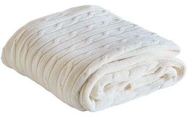 A neatly folded white knitted blanket with a cable pattern.
