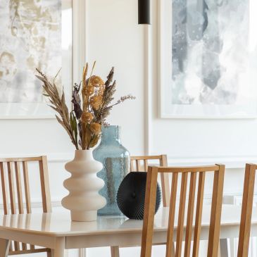 Modern dining table with artistic vases and wooden chairs.