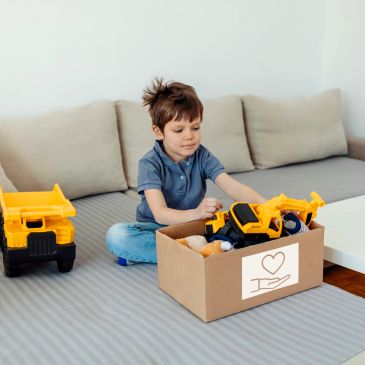 Boy packing toy trucks into donation box.