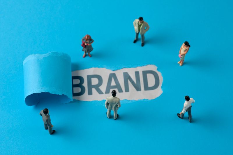 Business people figurines looking at the phrase "Brand"