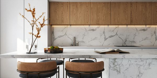 Modern kitchen with marble island, wooden cabinets, and leather bar stools.
